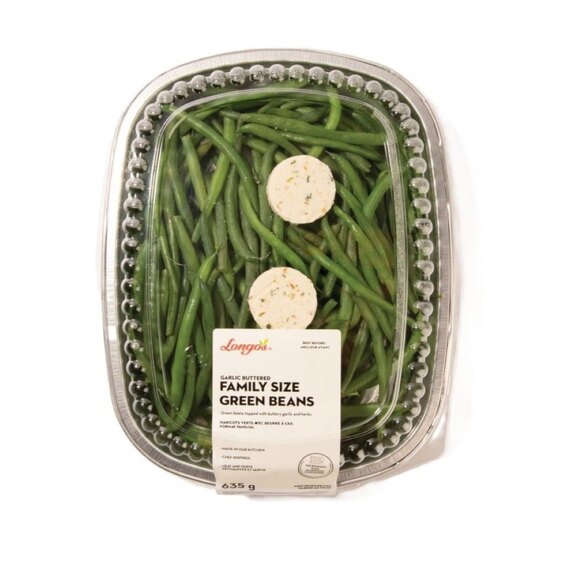 Family-size garlic butter green beans in a sealed ready-to-heat container, topped with herb butter for serving.